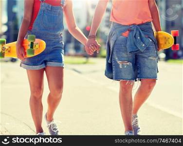 summer, relations, extreme sport and people concept - close up of happy teenage couple with short modern cruiser skateboards walking along city street. close up of young couple with skateboards in city