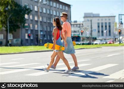 summer, relations, traffic, extreme sport and people concept - happy teenage couple with short modern cruiser skateboards crossing city crosswalk