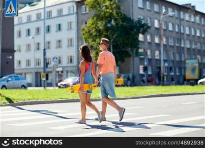 summer, relations, traffic, extreme sport and people concept - happy teenage couple with short modern cruiser skateboards crossing city crosswalk