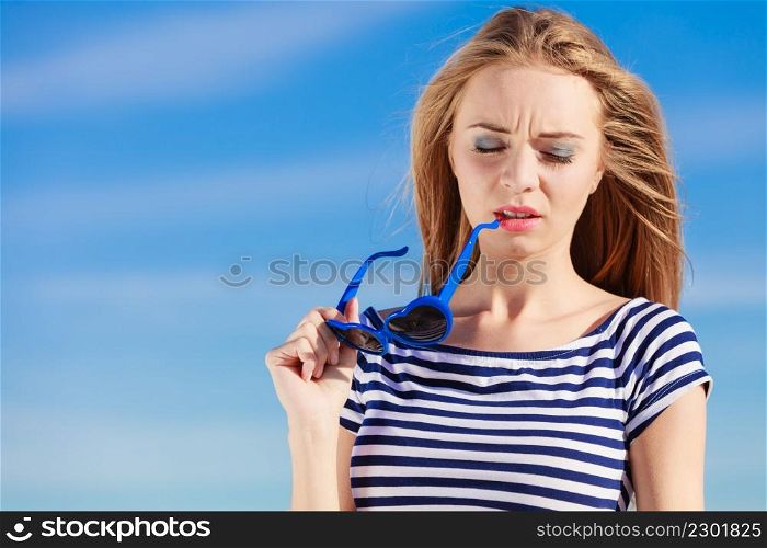 Summer relaxation concept.. Portrait girl with blue heart shaped sunglasses enjoying summer breeze outdoor on sky background
