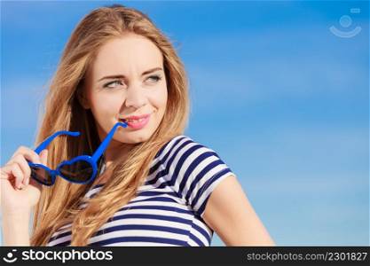 Summer relaxation concept.. Portrait girl with blue heart shaped sunglasses enjoying summer breeze outdoor on sky background