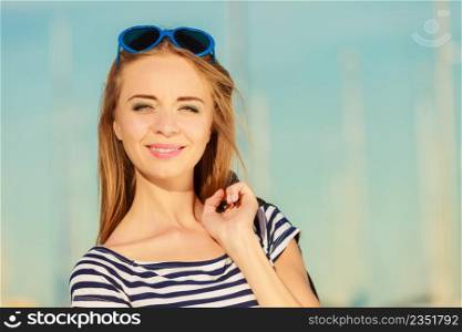Summer relaxation concept.. Portrait girl with blue heart shaped sunglasses enjoying summer breeze outdoor in marina