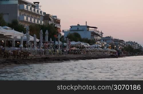 Summer resort in the evening. Hotels and cafes with calm sea in foreground. Recreation and summer vacation
