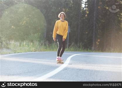 Summer Road Trip. beautiful landscape and view of a mountain road. girl fun rides on a skateboard at the transalpine. Romania.