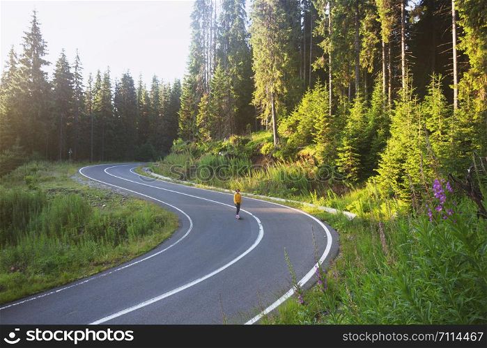 Summer Road Trip. beautiful landscape and view of a mountain road. girl rides on a skateboard at the transalpine. Romania.