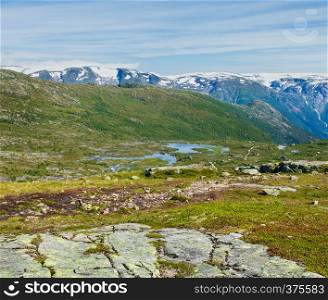Summer Roldal highlands plateau mountain landscape with small lakes and houses on slope (Norway, on hiking route to Trolltunga from Odda).