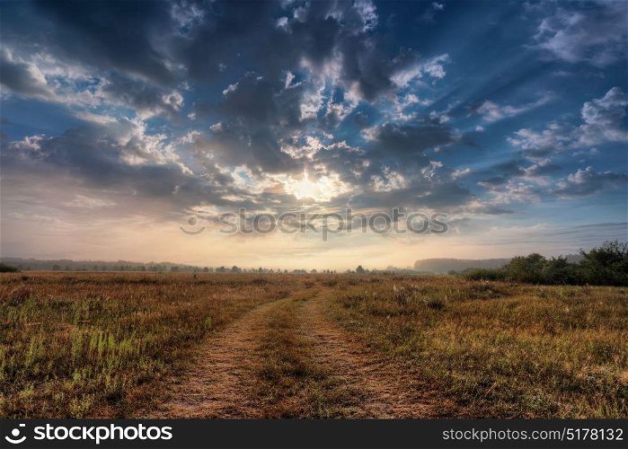 Summer rural landscape with sunrise and the road. Sunrise over the meadow