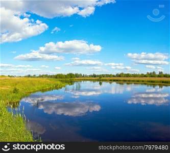 Summer rushy lake view with clouds reflections.