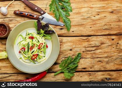 Summer salad of fresh zucchini, peppers, garlic and herbs.Vegetarian food on rustic wooden table.Copy space. Zucchini vegetable salad