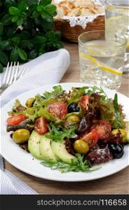 Summer salad - with avocado, olives, tomatoes in lettuce dressed, mustard-garlic sauce
