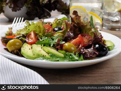 Summer salad - with avocado, olives, tomatoes in lettuce dressed, mustard-garlic sauce