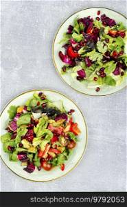 Summer salad with greens, pepper, red lettuce and cucumber, decorated with pomegranate. Flat lay. Salad of fresh vegetables and herbs.