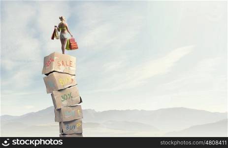 Summer sale. Beautiful young girl in bikini with shopping bags on pile of carton boxes