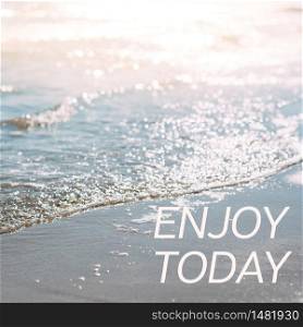 Summer sand beach and seashore waves background. Defocused blurred square holiday vacations concept with motivational quote Enjoy today