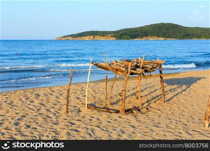 Summer sea coast (Bulgaria) view with sandy beach and small wooden awning from sun.