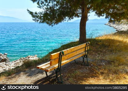 Summer sea coast landscape with bench under pine tree (Greece)