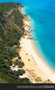 Summer sea coastal landscape with sandy Portinho beach. Top view from Nature Park of Arrabida in Setubal, Portugal. All peoples unrecognizable.