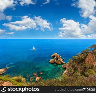 Summer sea rocky coast landscape with sailing catamaran, Costa Brava, Spain. View from above.
