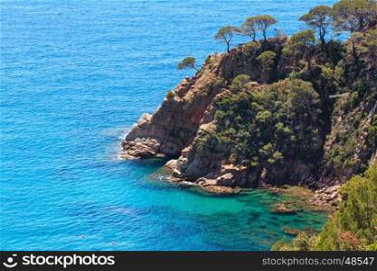 Summer sea rocky coast view with boat near shore (Spain).