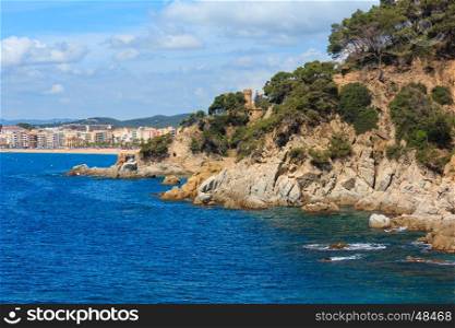 Summer sea rocky coast view with Castle of Sant Joan and Sa Caleta beach, Lloret de Mar town, Spain. People are unrecognized.