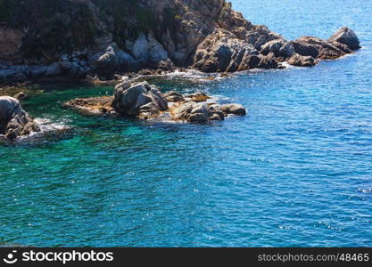 Summer sea rocky coast view with sunny sparkles on water surface (Spain).