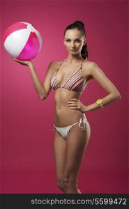 summer shoot of sexy lady posing with bikini, ponytail, yellow fashion wrist watch and pink beach ball in the hand
