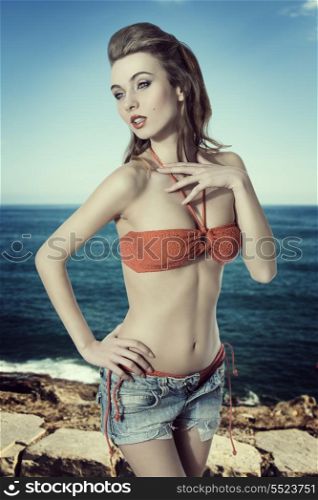 summer shoot of very pretty young woman with bikini and denim shorts, long hair-style and sensual pose