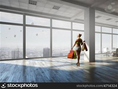 Summer shopping time. Young woman in swimsuit with shopping bags in modern office