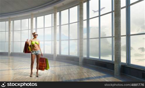 Summer shopping time. Young woman in swimsuit with shopping bags in modern office