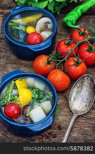 summer soup with fresh vegetables. traditional soup of fresh vegetables in blue pot on wooden background.Photo tinted