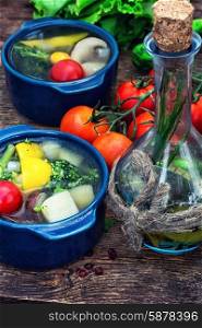 summer soup with fresh vegetables. traditional soup of fresh vegetables in blue pot on wooden background.Photo tinted
