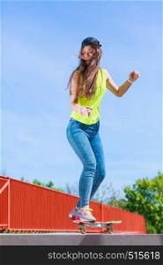 Summer sport and active lifestyle. Cool teenage girl in full length skater riding skateboard on the street. Outdoor.