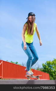 Summer sport and active lifestyle. Cool teenage girl in full length skater riding skateboard on the street. Outdoor.