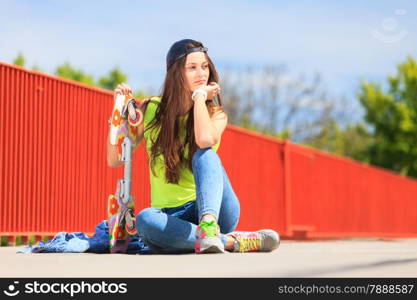 Summer sport and active lifestyle. Cool teenage girl skater sitting with skateboard on the street. Outdoor.