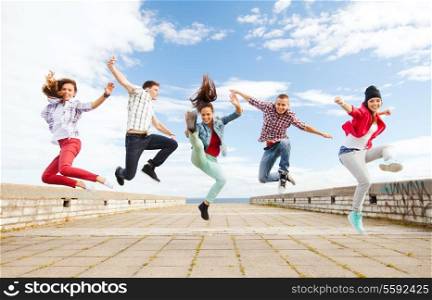 summer, sport, dancing and teenage lifestyle concept - group of teenagers jumping