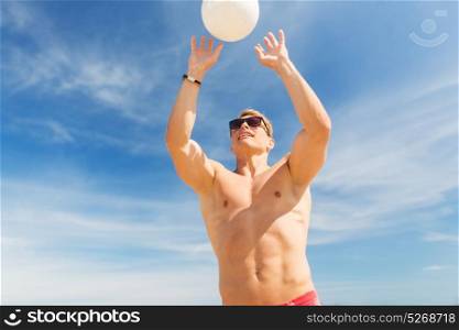 summer, sport, fitness and people concept - young man with ball playing volleyball on beach. young man with ball playing volleyball on beach