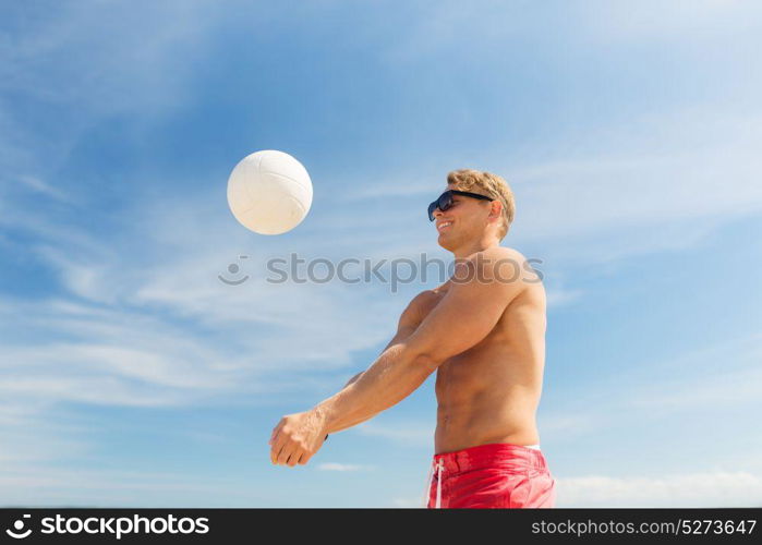 summer, sport, fitness and people concept - young man with ball playing volleyball on beach. young man with ball playing volleyball on beach