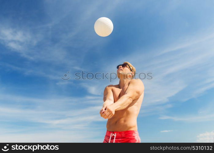 summer, sport, fitness and people concept - young man with ball playing volleyball on beach. young man with ball playing volleyball on beach