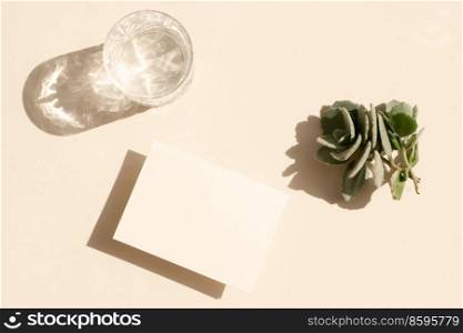 summer stationery mock-up scene. Blank business card and glass of clear water on beige textured table background, toned. summer stationery mock-up scene.