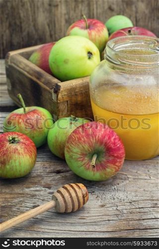 Summer still life of apples and honey. Delicious apples from the summer harvest amid jars of honey