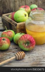 Summer still life of apples and honey. Delicious apples from the summer harvest amid jars of honey