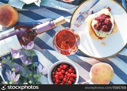 Summer still life-   picnic on a wooden pier. wine, sinabones, peaches, a book with a lake view 