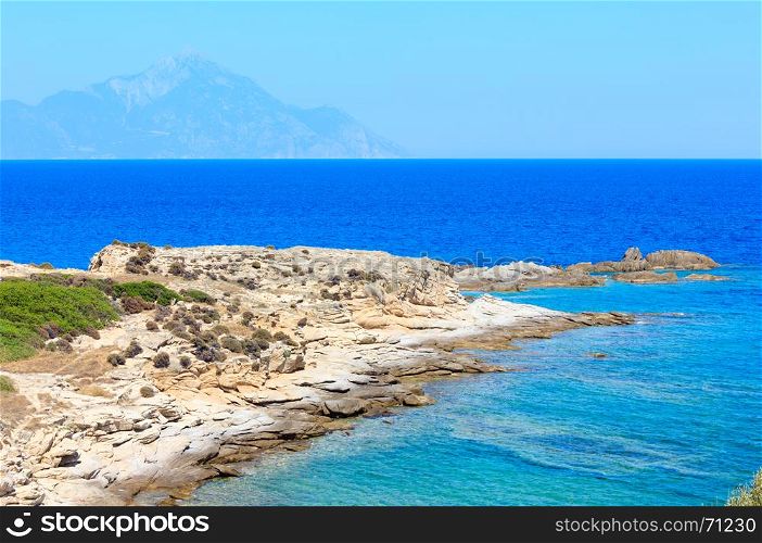 Summer stony sea coast landscape with Atthos mount view in far(Halkidiki, Sithonia, Greece).