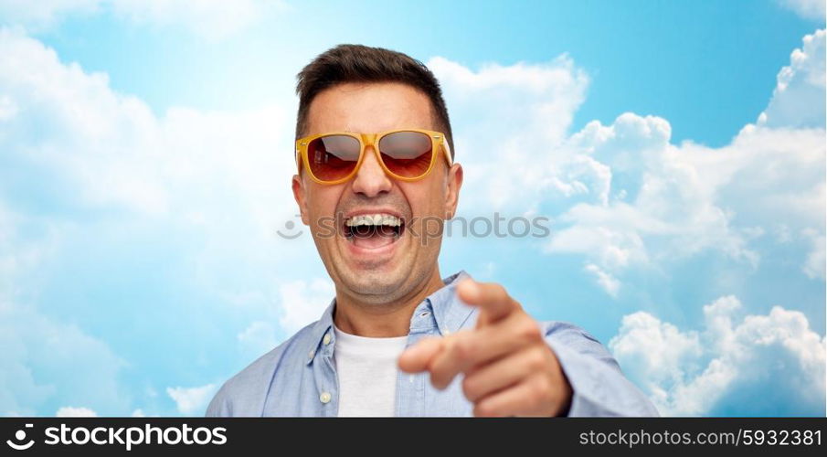 summer, style, emotions and people concept - face of laughing middle aged latin man in shirt and sunglasses over blue sky and clouds background