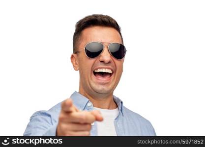 summer, style, emotions and people concept - laughing man in sunglasses pointing finger on you