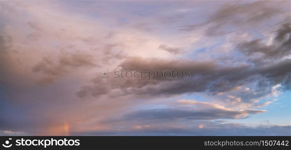 Summer sunset after rain sky panorama with fleese purple clouds and rainbow. Evening dusk good weather natural background.
