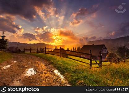 Summer sunset in mountain village. Beautiful colorful evening after rain. Stormy clouds in summer sunlight. Alpine scene with a house in a mountain valley