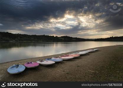 Summer sunset over lake in landscape with leisure boats on shore