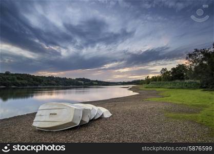 Summer sunset over lake in landscape with leisure boats on shore