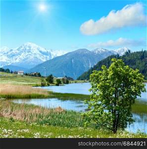 Summer sunshiny mountain landscape with lake Lago di Resia and blue cloudy sky (Italy). Two shots stitch image.